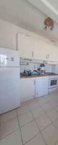 una cucina con elettrodomestici bianchi e pavimento bianco di agreable appartement situe en front de mer a Soulac-sur-Mer Altre 4 foto