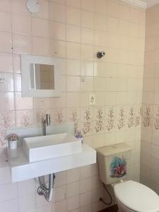 une salle de bain avec un lavabo et des toilettes dans l'établissement Apt Guarujá Praia Pitangueiras, à Guarujá