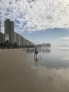 une personne debout sur le sable sur une plage dans l'établissement Apt Guarujá Praia Pitangueiras, à Guarujá