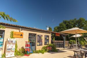 a restaurant with an umbrella and tables and chairs at Camping Le Mas de Sireuil in Sireuil +36 photos