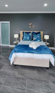 a bedroom with a large bed with blue sheets at Hartklop Luxury Self Catering Guesthouse in Linkside