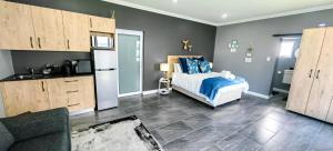 a bedroom with a bed and a kitchen with a refrigerator at Hartklop Luxury Self Catering Guesthouse in Linkside