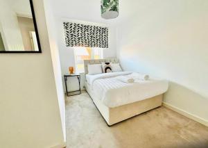 a bedroom with a white bed with a window at Honeybee Haven Retreat - 3 Bed House in Ashford