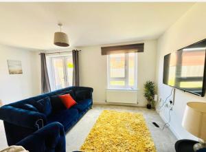 a living room with a blue couch and a tv at Honeybee Haven Retreat - 3 Bed House in Ashford