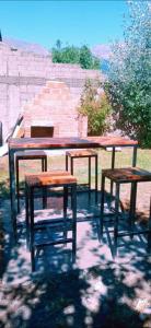 Una mesa de picnic y dos taburetes junto a una pared. en Ty Hapus, en El Bolsón 2 fotos más