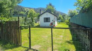 una pequeña casa blanca detrás de una valla en Ty Hapus, en El Bolsón