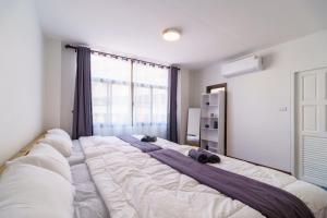 un grande letto bianco in una stanza con una finestra di Charming 3-Storey house near BTS Onnut Station a Bangkok Altre 48 foto