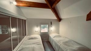 two beds in a room with a window at Maison forêt et piscine, les Mas de Vertmarines in Saint-Jean-de-Monts