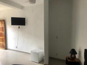a living room with a television on a white wall at Pousada Recanto Três Coqueiros in Boicucanga