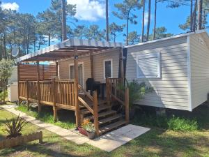 a tiny house with a porch and a deck at MH 535 Tout équipé 3 CHAMBRES 1 SDB dans camping 4 étoiles in Saint-Julien-en-Born