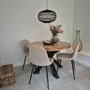 una mesa de comedor con sillas y un jarrón de flores en Het Klokkenest, en Katwijk aan Zee