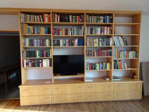 ein Bücherregal mit einem TV darüber in der Unterkunft Hotel-Pension Schlossgarten in Trippstadt