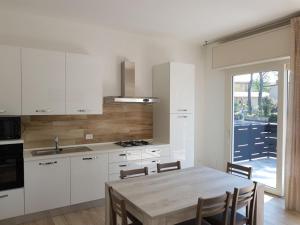 a kitchen with white cabinets and a wooden table at Dalila in Rosolina