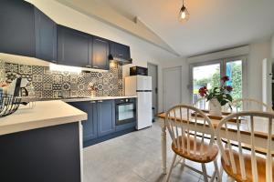 a kitchen with blue cabinets and a table and chairs at Le Fief des Roses in Les Mathes
