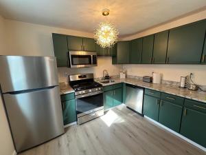 a kitchen with green cabinets and a stainless steel refrigerator at 2BR Modern Home - Near WVU, Hospitals & Stadium in Morgantown