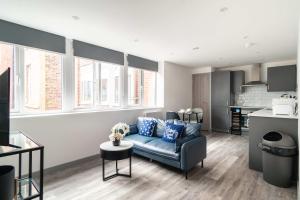 a living room with a blue couch and a kitchen at Convenient 1 Bedroom Apartment in Preston Centre in Preston