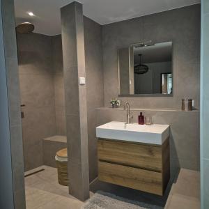 un baño con lavabo y espejo en Het Klokkenest, en Katwijk aan Zee 5 fotos más