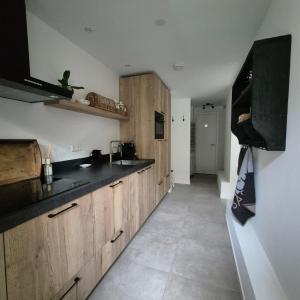 a kitchen with wooden cabinets and black counter tops at Het Klokkenest in Katwijk aan Zee