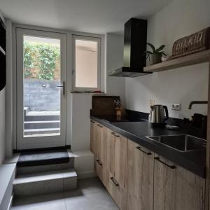 a kitchen with a sink and a door to a yard at Het Klokkenest in Katwijk aan Zee +5 photos
