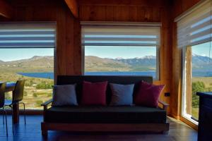 a couch in a room with windows with mountains at Cabañas Lodge Puerta Roja in Los Helechos
