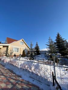 una recinzione coperta di neve davanti a una casa di Ak Orgo House a Karakol