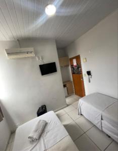 a hotel room with two beds and a television at Shopping 44 Hotel in Goiânia