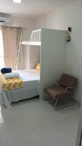 a bedroom with a bunk bed and a chair at Flat Bervely Hills 308 in Vila Velha