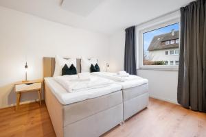 a bedroom with two white beds and a window at LudwigsCozyEscape - Ruhiges Design-Apartment mit Balkon & Parkplatz, 4 Gäste, SmartTV in jedem Zimmer, Highspeed WLAN, Workspace, 24h Self Check-in in Ludwigsburg