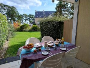 a table with a bowl of fruit on a patio at A 03 Pool apartment with sea view in Fouesnant