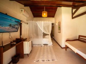 a bedroom with a bed with a mosquito net at Pousada Casa da Praia in Caraíva