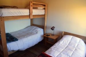 a bedroom with two bunk beds and a table at Cabañas Lodge Puerta Roja in Los Helechos