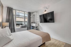 Un dormitorio con una cama y un televisor en una pared. en Initial / Orignal / Québec, en Quebec