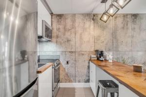 una cocina con armarios blancos y una pared de hormigón en Initial / Orignal / Québec, en Quebec