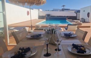 stół z kieliszkami do wina i basen w obiekcie Villa Nepal w mieście Playa Blanca