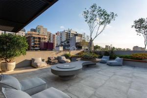 a patio with couches and a table on a rooftop at Apartamento completo localizado em um dos melhores bairros de Porto Alegre. in Auxiliadora