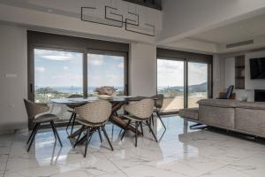 a dining room with a table and chairs and windows at Aetheria Luxury Villa in Kalithies
