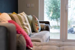 a couch with pillows sitting next to a window at 3-Bed House in Dublin City Centre in Dublin