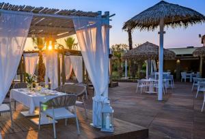a patio with tables and chairs and umbrellas at Pareus Beach Resort in Caorle