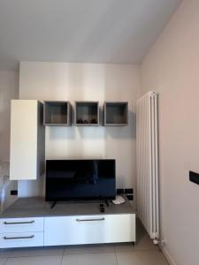 a living room with a tv and a white wall at GARDA LIVING APARTMENTS Riva del Garda in Riva del Garda
