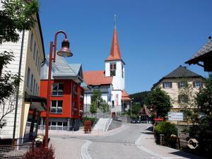 a street in a town with a church with a steeple at Ferienwohnung Brasil, 76 Qm in Schonach