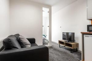 a living room with a black couch and a tv at Budget 1 Bed Flat in Halifax Centre in Halifax