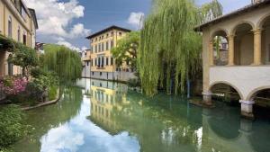a view of a river with buildings and a bridge at Cozy Place Sacile Centre Parking & AC in Sacile