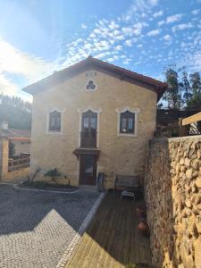 a large stone building with a bench in front of it at Quinta dos Milagres Casa dos Bigodes in Friumes