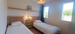 2 letti in una camera con 2 finestre di Heron- Maison avec jacuzzi privatif 4pers a Les Sables-dʼOlonne