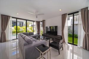 a living room with a gray couch and a television at Private pool villa bangtao - laguna park in Ban Phru Champa