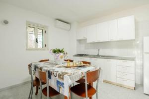 a white kitchen with a table and chairs at Residence Family House in Vieste