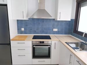 a kitchen with white cabinets and a stove top oven at Casa El Cuartel with private seaview rooftop in Conil de la Frontera