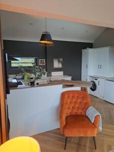 a kitchen with an orange chair and a counter at Rose Meadow Lodge in Liscannor +30 photos