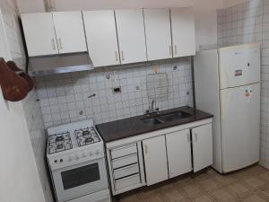 eine Küche mit weißen Schränken, einem Herd und einem Kühlschrank in der Unterkunft Andino in La Cieneguita