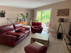 a living room with a leather couch and chairs at Villa en pleine nature avec piscine in Sablières